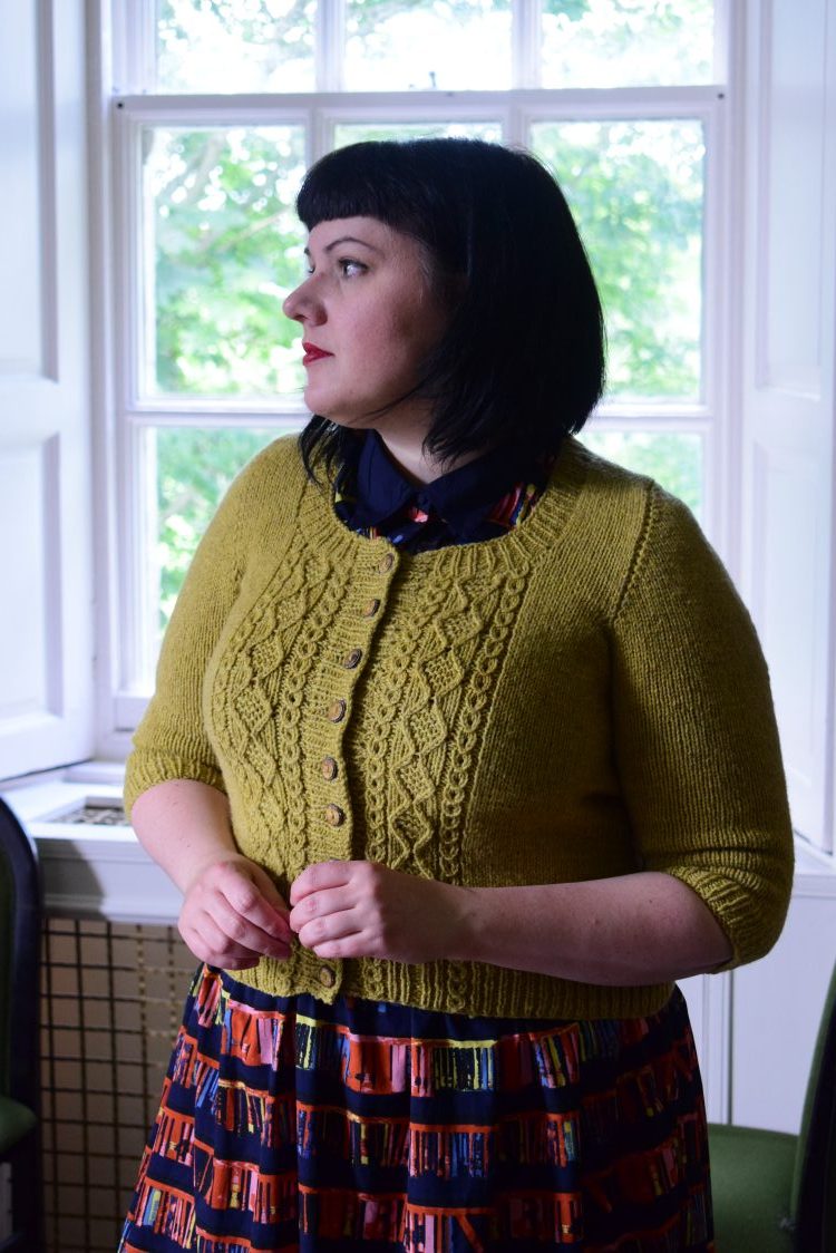 Karie Westermann wearing her Incunabula cardigan which is mustard yellow with cables creating texture down the front. 