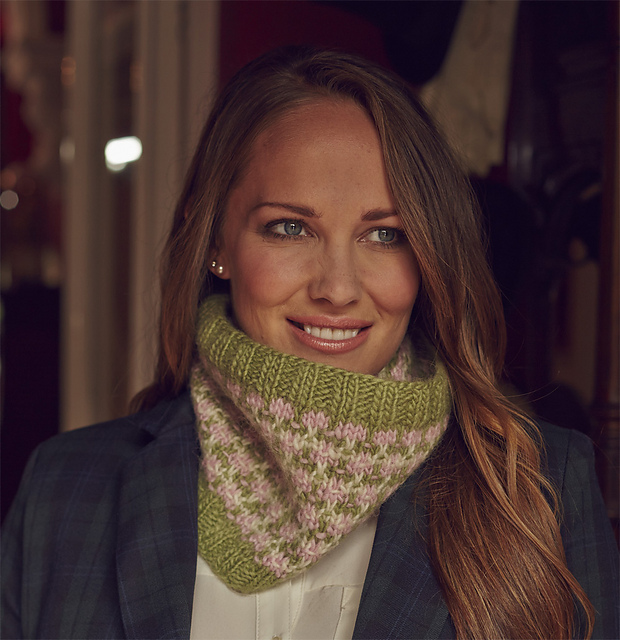 Woman with long hair wears Shona cowl - handknit in green, pink and cream with repeating motif